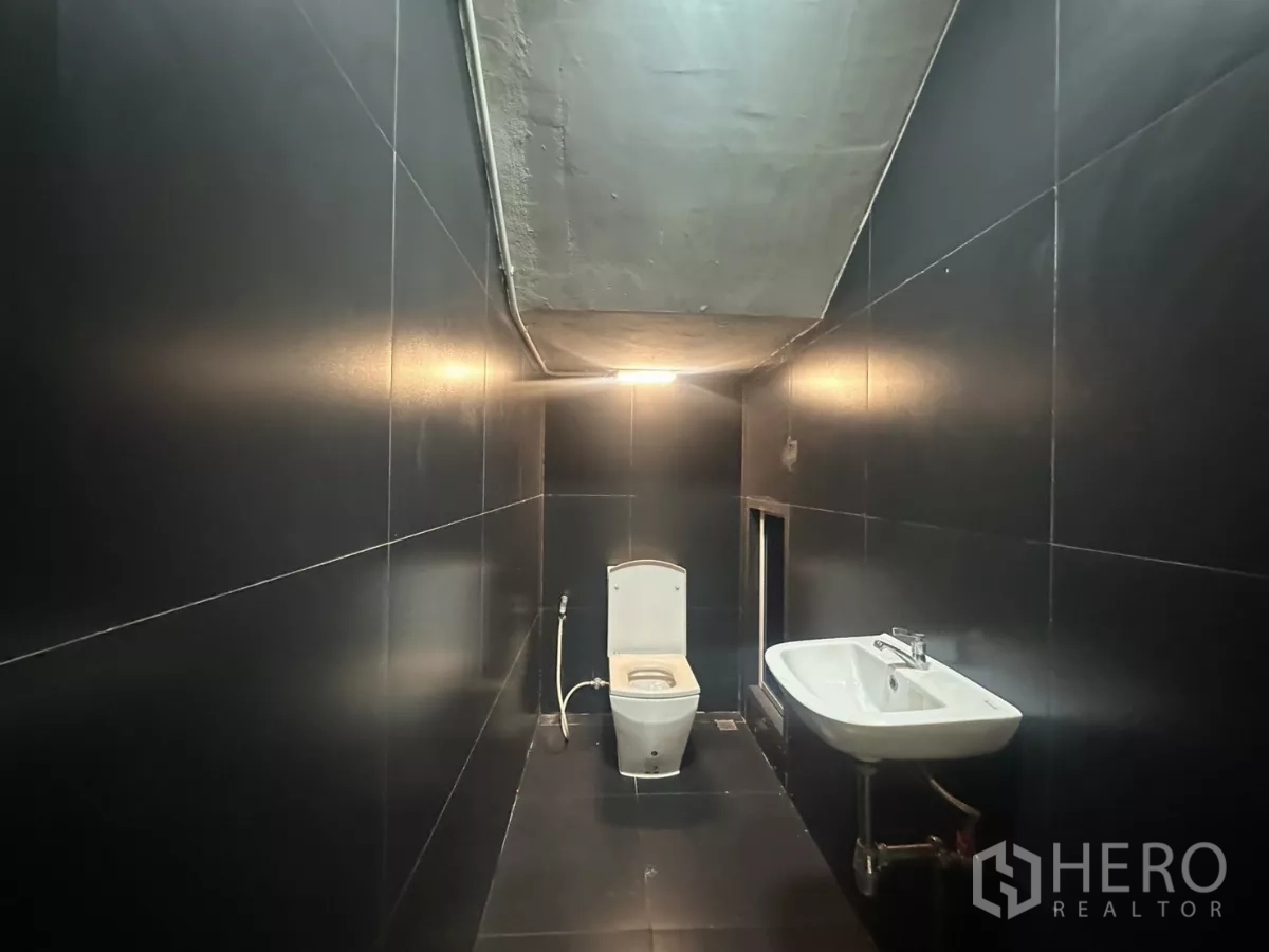 带办公室的家 出租在Pathum Wan, Bangkok - 黑色瓷砖卫浴，坐便与挂墙式洗手盆，顶高较低。