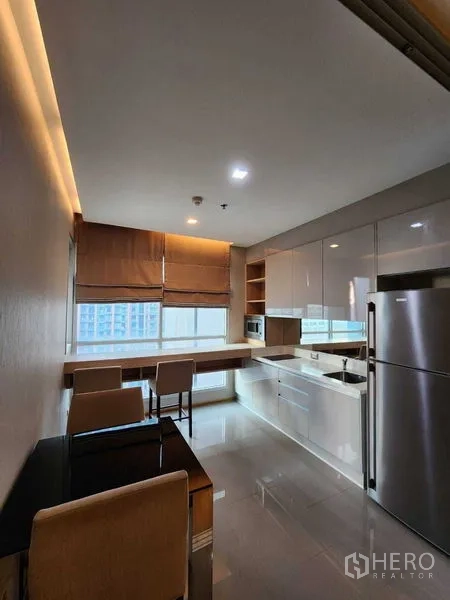 公寓 出售在Ratchathewi, Bangkok - 开放式厨房与用餐区，配大冰箱、微波炉、亮面柜体与观景窗。
