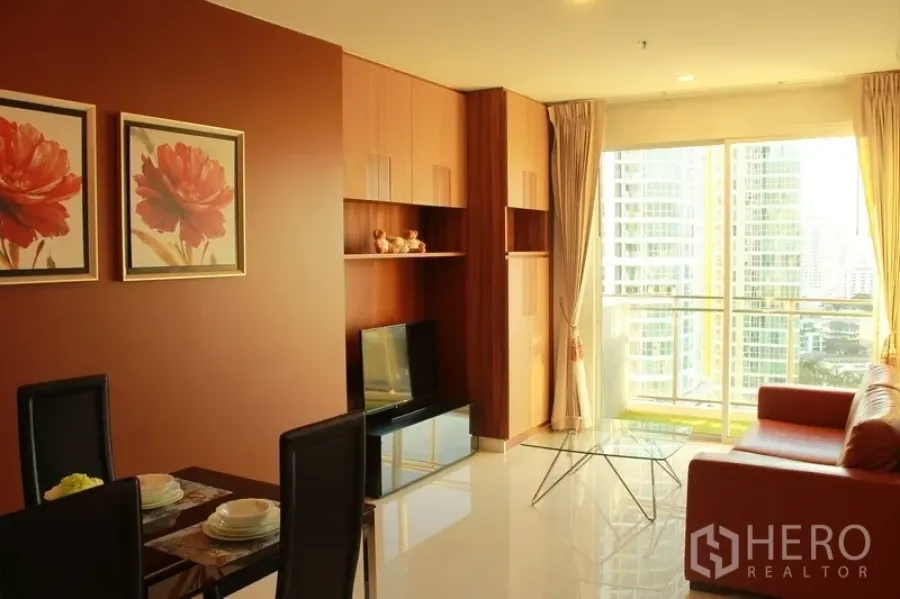 公寓 出租在Watthana, Bangkok - 开放式客厅，内置收纳与餐桌，阳台可观周边高楼景致。