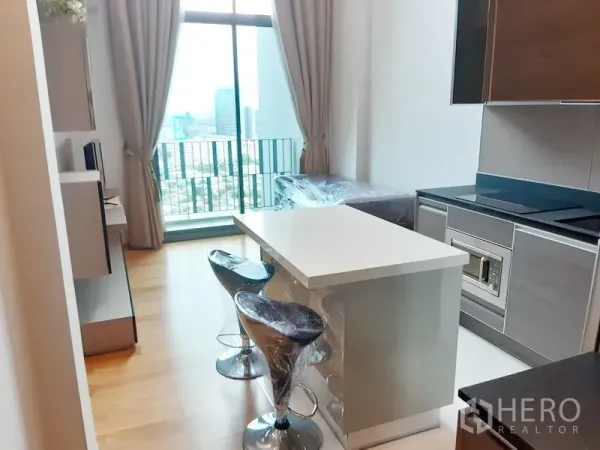 公寓 出租在Khlong Toei, Bangkok - 明亮客厅与现代中岛厨房，落地窗可眺望曼谷空堤区城市天际线。