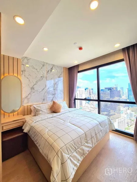 Condominium for rent in Bang Rak, Bangkok - Bedroom angle showing built-in wardrobe, marble headboard and city outlook.