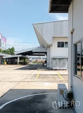 Warehouse for rent or sale in Lam Luk Ka, Pathum Thani - Side driveway next to the warehouse showing covered loading canopy and clear truck access.