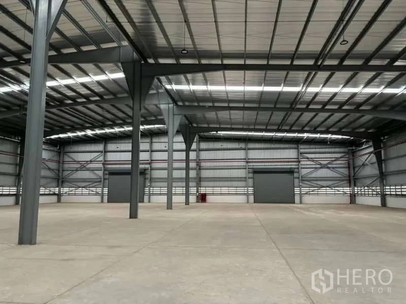 货栈 出租在Nikhom Phatthana, Rayong - 高挑钢结构仓库内部，抛光混凝土地面与大型卷闸门