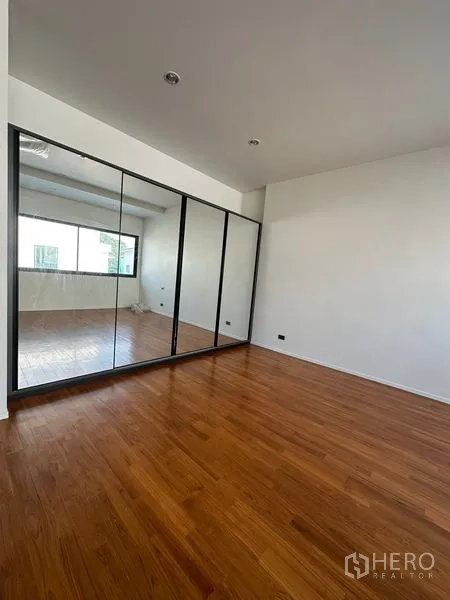 独立式住宅 出租在Watthana, Bangkok - 卧室配整面镜门衣柜与抛光木地板。