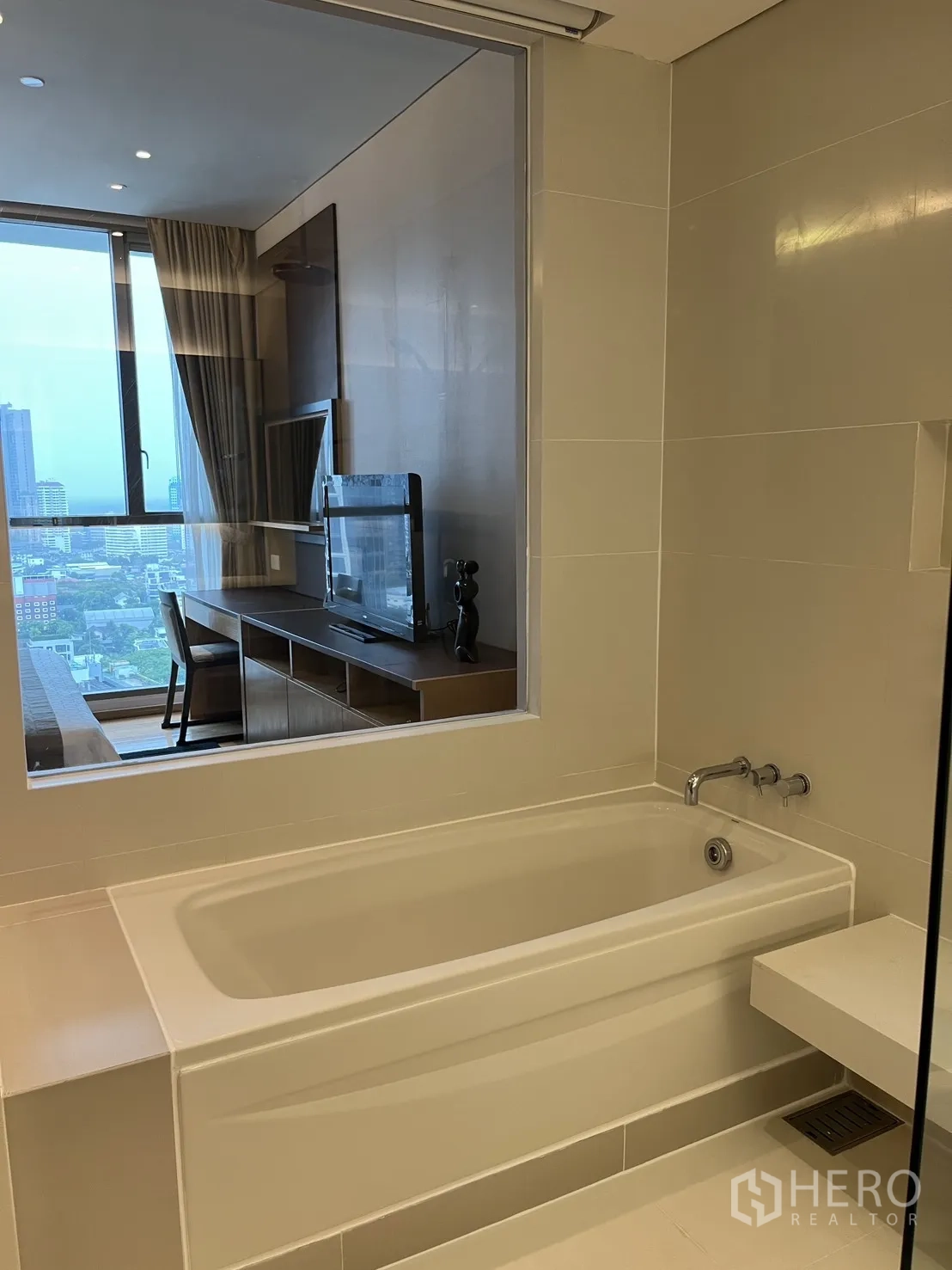 Condominium for rent in Watthana, Bangkok - Bathroom with soaking tub and a window to the bedroom and city view.