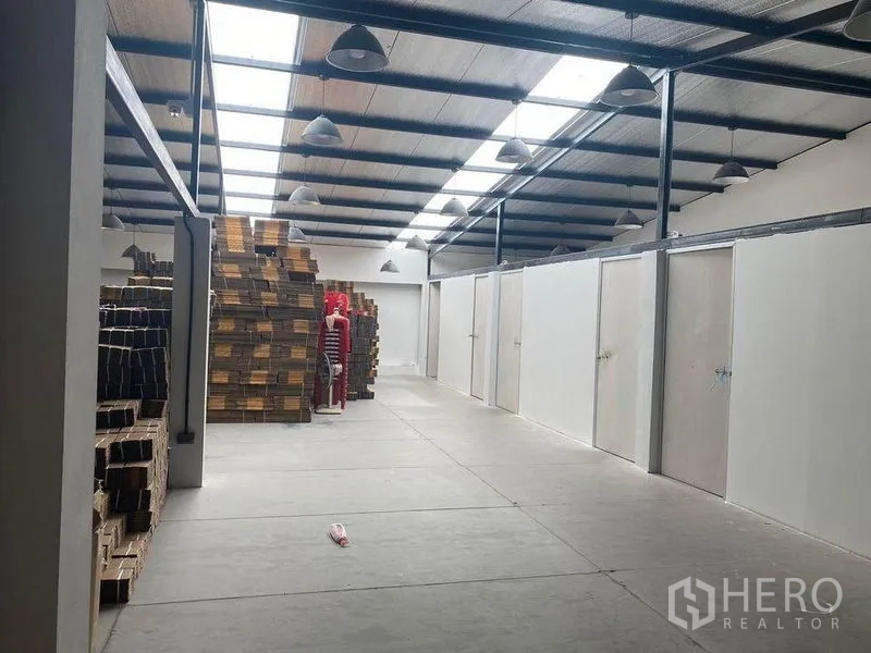 Home Office for rent or sale in Bang Khae, Bangkok - Warehouse hall with skylights, stacked boxes and partitioned storage rooms.