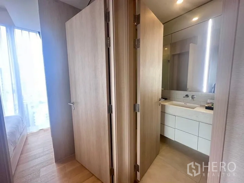 Condominium for rent - Wooden-door hallway connecting bedroom and bathroom with vanity and mirror cabinet.