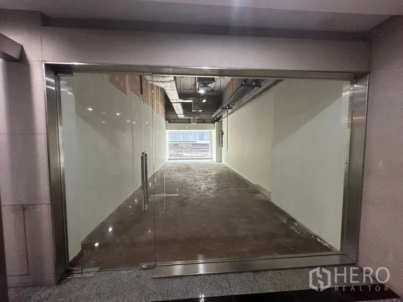 Retail Space for rent in Watthana, Bangkok - Ground-floor retail unit with full-height glass storefront, stainless frame, and long rectangular shell space.