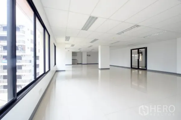 Office Space for rent in Chatuchak, Bangkok - Open office interior with rows of black‑framed windows and a glass door.