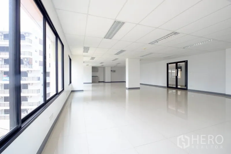 Office Space for rent in Chatuchak, Bangkok - Open office interior with rows of black‑framed windows and a glass door.