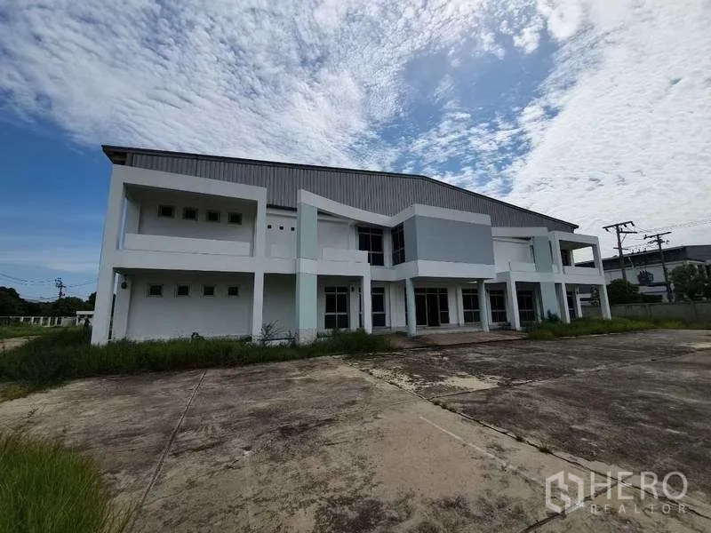 Factory for rent in Mueang Samut Prakan, Samut Prakan - Front elevation showing the two‑storey office block attached to the factory and a wide concrete forecourt.
