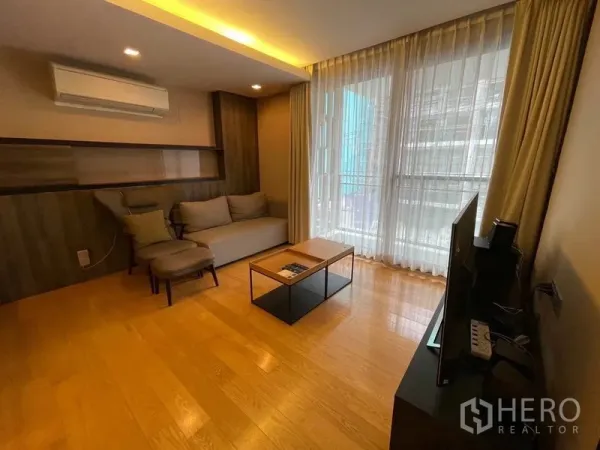 公寓 出售在Watthana, Bangkok - 温馨客厅，配沙发、电视与落地窗帘。