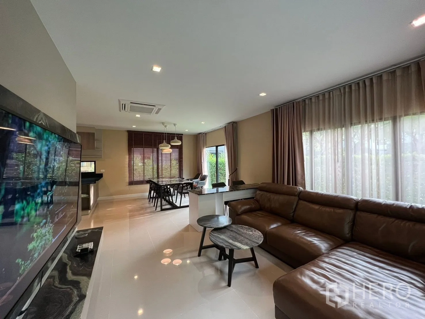 บ้าน ให้เช่าในBang Phli, Samut Prakan - ห้องนั่งเล่นแบบโอเพ่นแพลน โซฟาหนังขนาดใหญ่ ผนังทีวี และหน้าต่างบานกว้าง