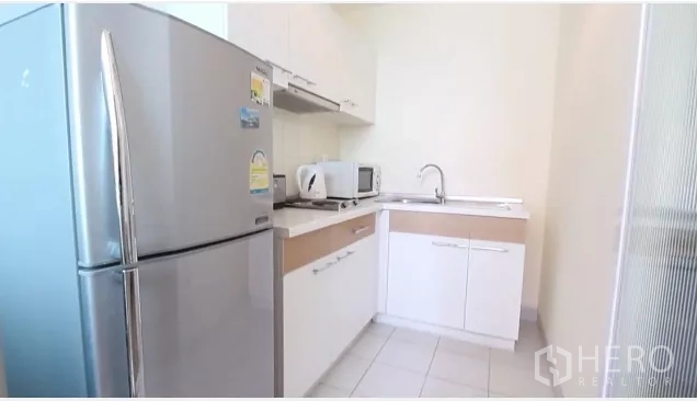 公寓 出租在Watthana, Bangkok - 独立L型厨房，白色橱柜、不锈钢大冰箱与水槽、微波炉。