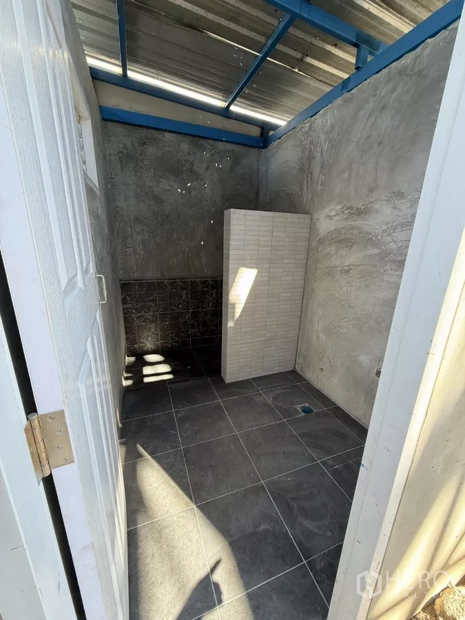 Warehouse for rent in Lam Luk Ka, Pathum Thani - Another view of the tiled restroom with partition and polished grey floor.