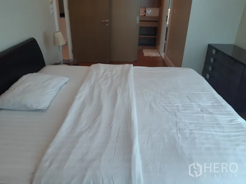 Condominium for rent in Khlong Toei, Bangkok - Bedroom from another angle showing bed, dresser, and doorway leading to closet or ensuite.