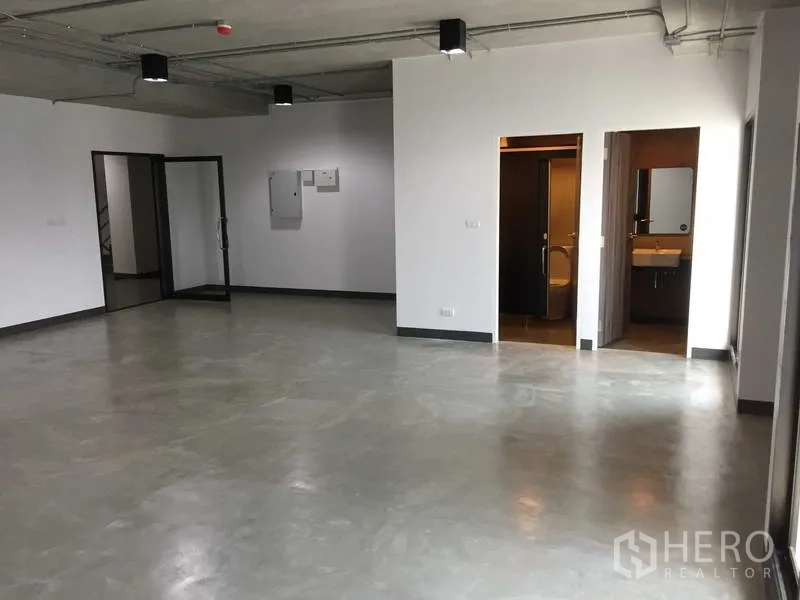 办公空间 出租在Khlong Toei, Bangkok - 宽敞办公区，通往卫生间与玻璃门的入口，可见水泥地与外露天花。