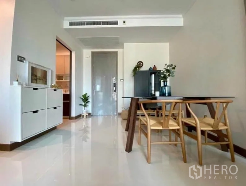 Condominium for rent in Watthana, Bangkok - Minimalist dining area with wooden table and chairs, glossy tile floors and entry door.