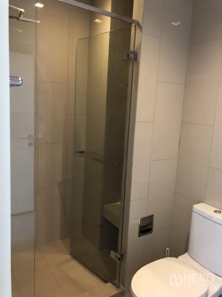 Condominium for rent in Watthana, Bangkok - Modern bathroom with glass‑enclosed shower and white sanitary ware.