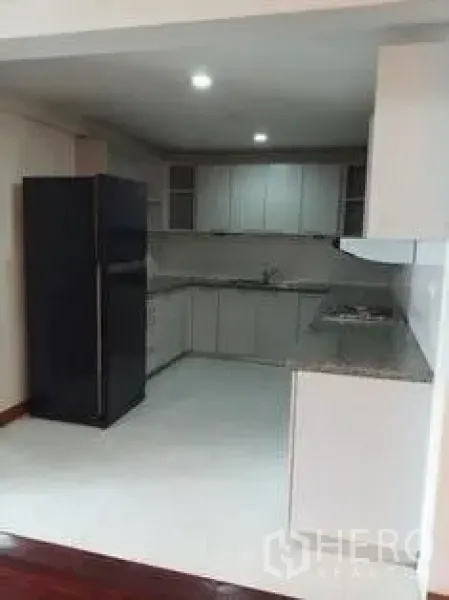 房间 出租在Pathum Wan, Bangkok - 独立U型厨房，白色橱柜、花岗岩台面与大冰箱。