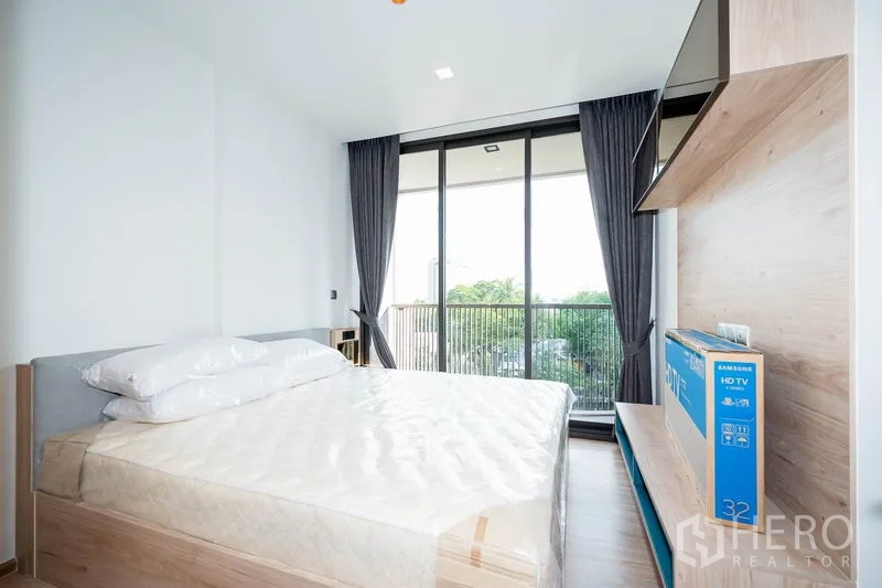 Condominium for rent in Watthana, Bangkok - Second bedroom with bed, wall shelf and large glass doors to the balcony.