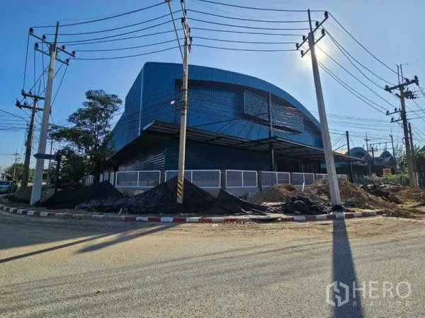 โรงงาน ให้เช่าในChon Buri - มุมเอียงของโรงงานสีน้ำเงิน มีกันสาดลานขนถ่ายและเสาไฟ