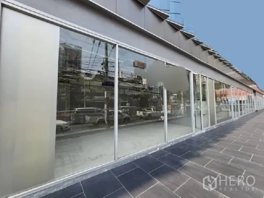 Retail Space for rent - Street-facing retail frontage with full-height glass windows along a wide tiled walkway in Phra Khanong.