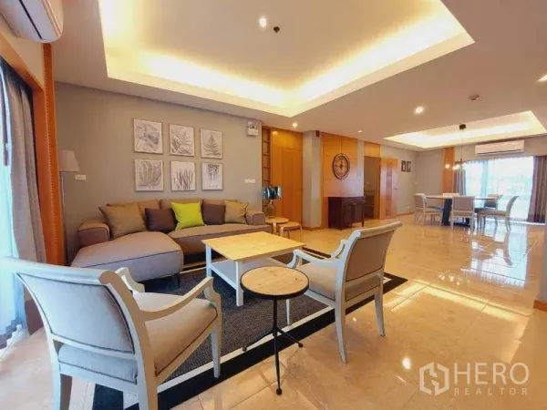 Apartment for rent - Open-plan living and dining room with cove lighting, sofa set, armchairs, coffee table and large windows.