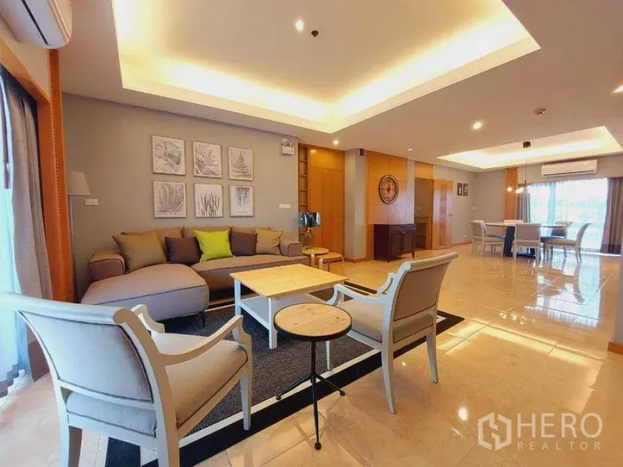 Apartment for rent - Open-plan living and dining room with cove lighting, sofa set, armchairs, coffee table and large windows.
