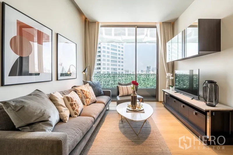 公寓 出租在Bang Rak, Bangkok - 采光充足的客厅，落地窗框出城市景观，配电视柜与温暖色调。