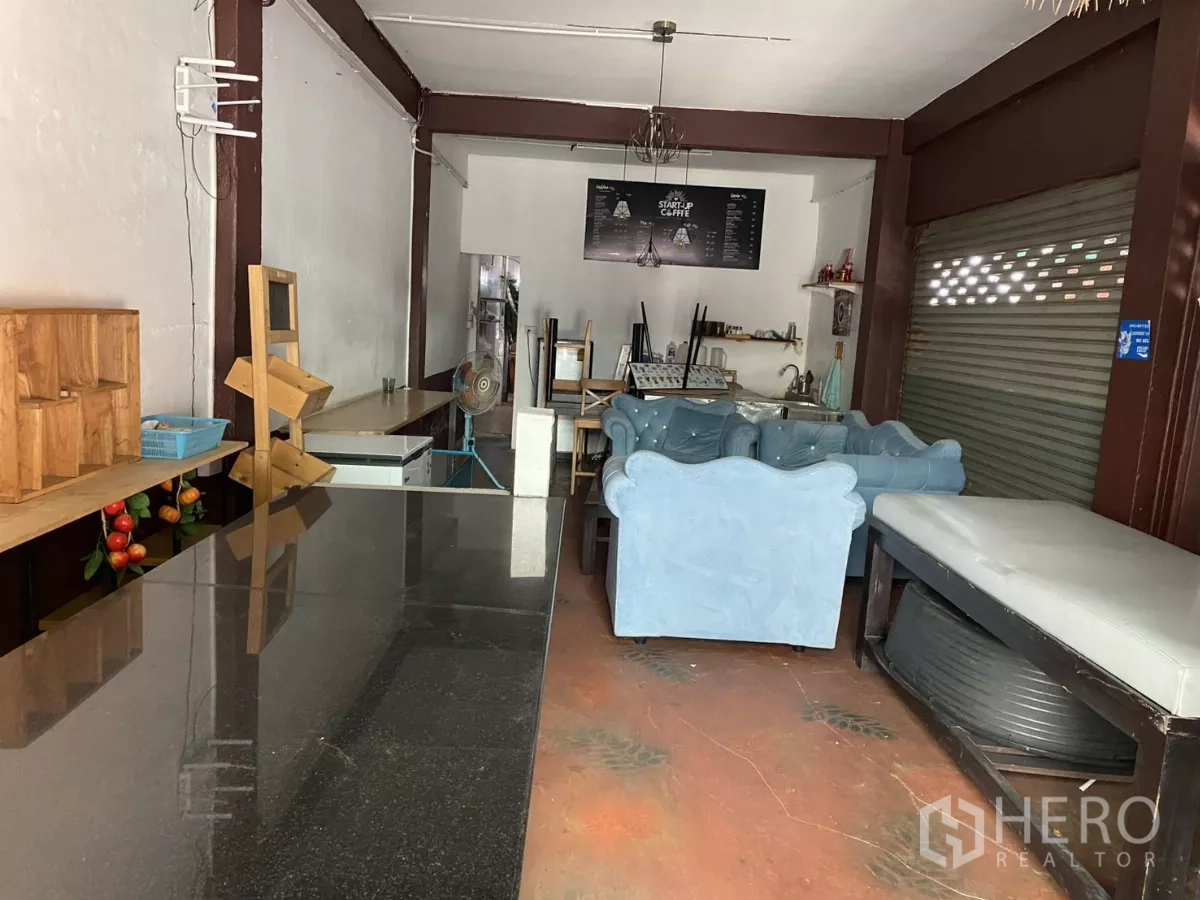 Shophouse for rent in Khlong Toei, Bangkok - Front retail hall with long counter, lounge seating and roller shutter.