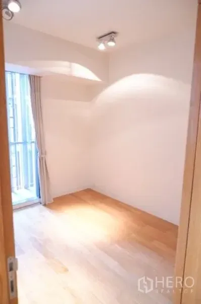 Condominium for sale in Sathon, Bangkok - Compact second bedroom or study with window and spotlighting over wood flooring.
