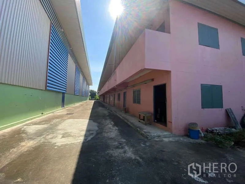 货栈 出租在Lat Lum Kaeo, Pathum Thani - 仓库与粉色员工宿舍之间的通道，阳光强烈。