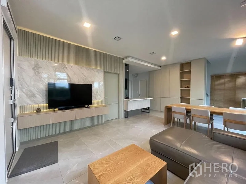 Detached House for rent in Prawet, Bangkok - Contemporary living room featuring a marble TV wall, built‑in cabinetry and recessed lighting.