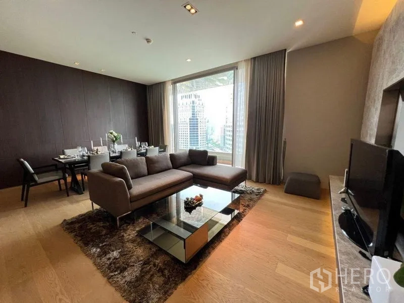 公寓 出租在Bang Rak, Bangkok - 起居区配L形沙发与餐桌，大窗框出摩天楼景。