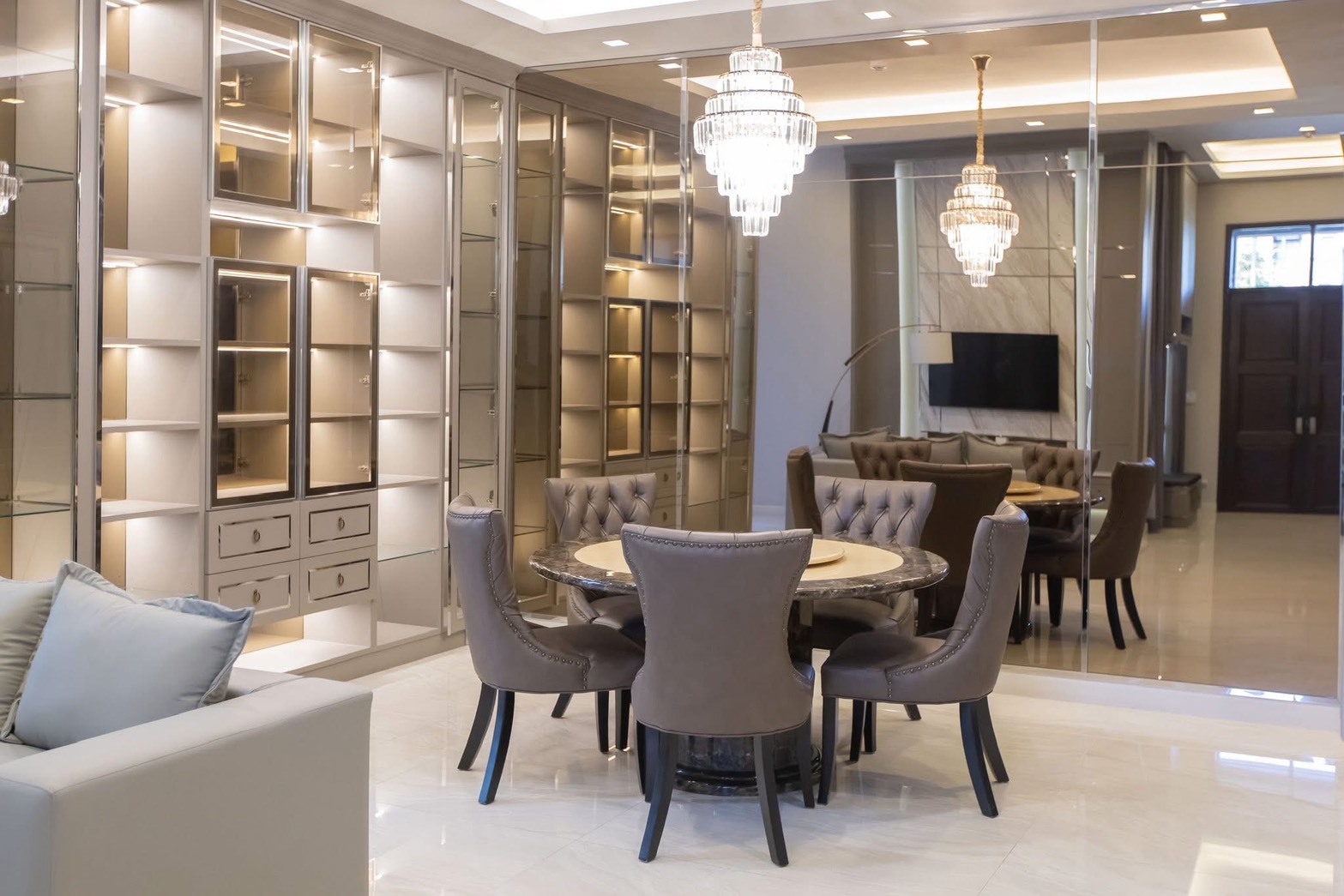 Detached House for rent in Lat Phrao, Bangkok - Elegant dining room with round marble table, tufted chairs, crystal chandeliers, and illuminated cabinets.