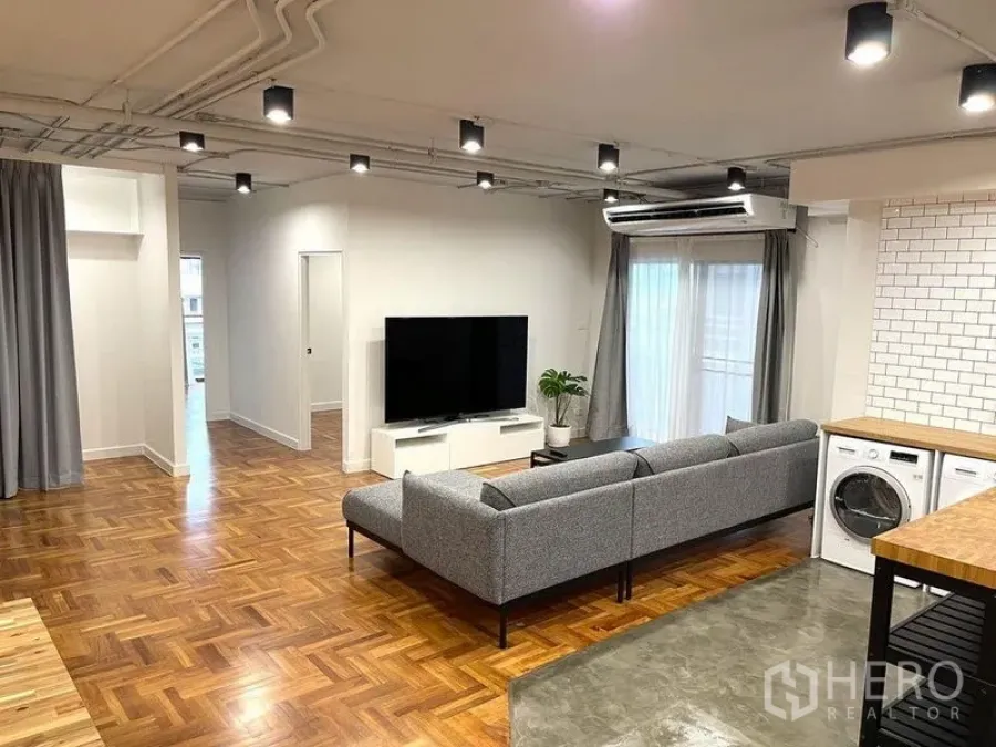 公寓 出租在Watthana, Bangkok - 明亮客厅，拼花木地板、空调与大屏电视。