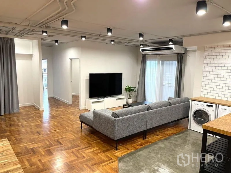 公寓 出租在Watthana, Bangkok - 明亮客厅，拼花木地板、空调与大屏电视。