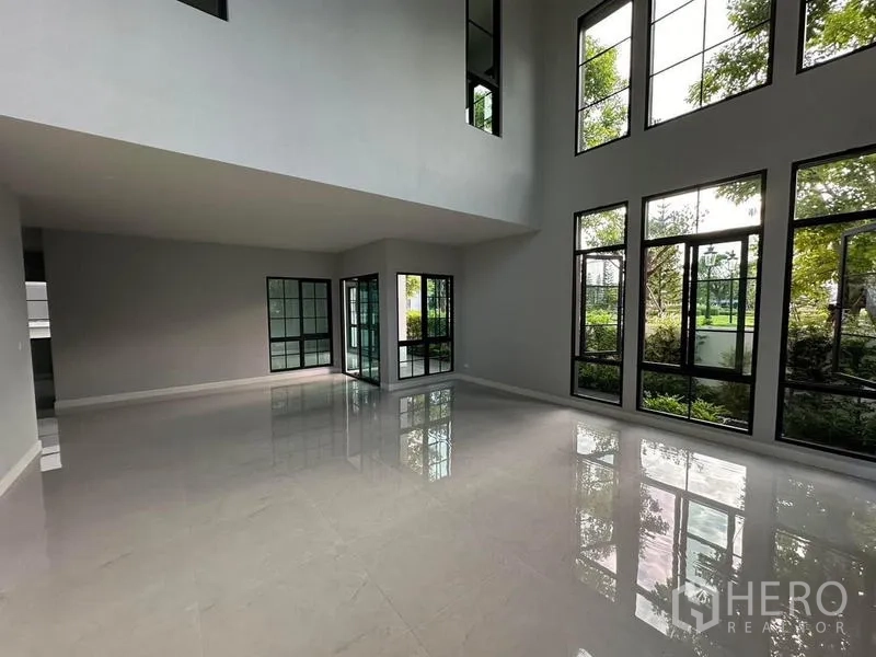 Detached House for rent or sale in Bang Phli, Samut Prakan - Double-height living room with floor-to-ceiling windows bringing garden views and natural light.