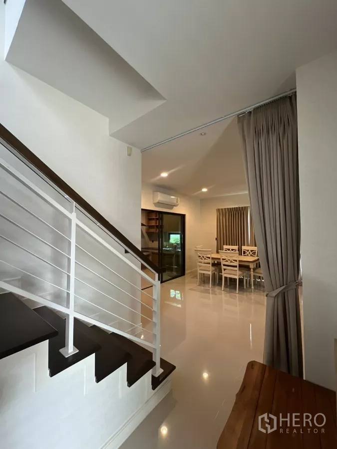 Detached House for rent in Bang Kapi, Bangkok - Staircase with white railing leading toward the open dining space and kitchen.