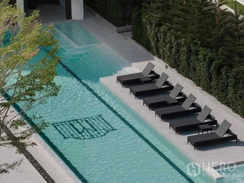 Detached House for sale in Saphan Sung, Bangkok - Long lap pool with row of black sun loungers and privacy hedge.