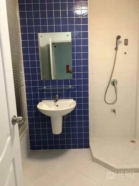Townhouse for rent in Wang Thonglang, Bangkok - Secondary bathroom with blue tiled wall, pedestal sink and shower.