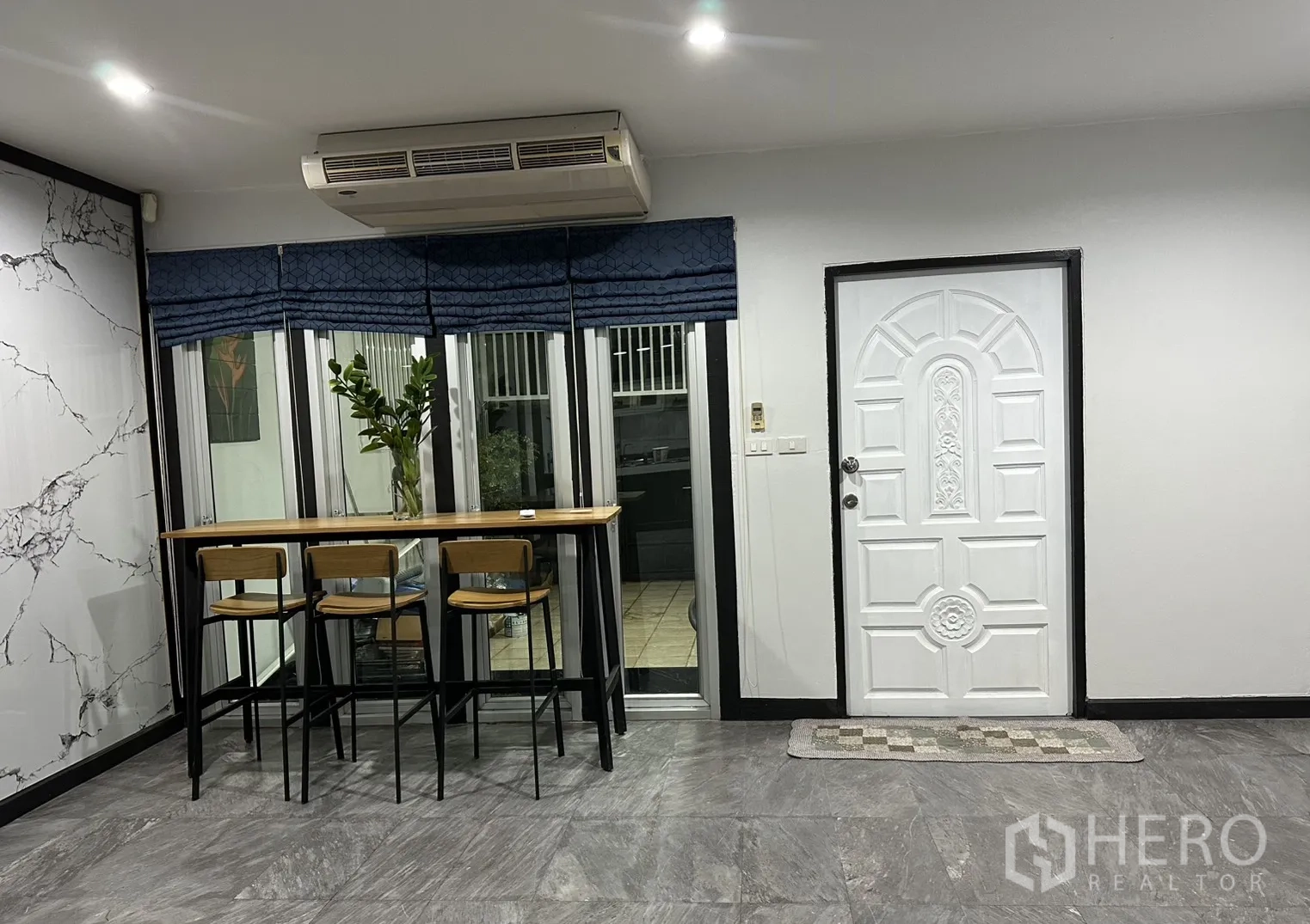 Home Office for rent in Khlong Toei, Bangkok - Entry area with bar seating by the windows and a paneled white door.