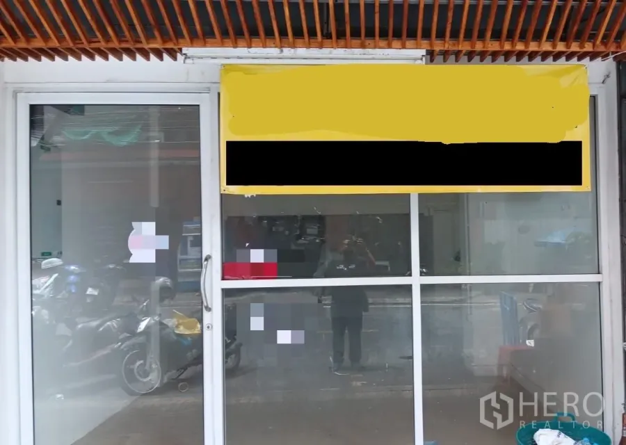 Shophouse for rent in Khlong Toei, Bangkok - Street-facing shophouse facade in Khlong Toei with large glass storefront, sliding door and signboard.