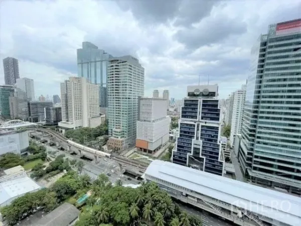 Condominium for rent or sale - Panoramic Bangkok skyline with BTS tracks and a station below amid Sathorn–Silom high-rise towers.