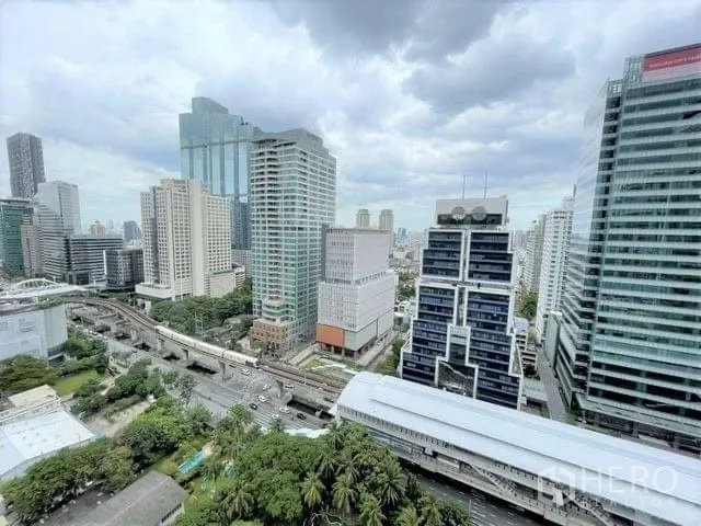 Condominium for rent or sale - Panoramic Bangkok skyline with BTS tracks and a station below amid Sathorn–Silom high-rise towers.
