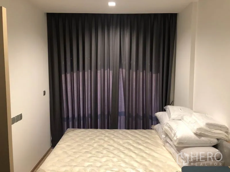 Condominium for rent in Watthana, Bangkok - Cozy bedroom with queen bed, dark blackout curtains, and stacked pillows.
