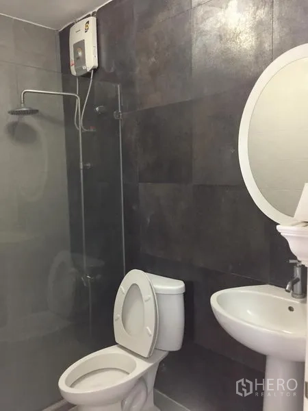 Townhouse for rent in Chatuchak, Bangkok - Modern bathroom with dark tiles, glass shower screen, rain shower and water heater.