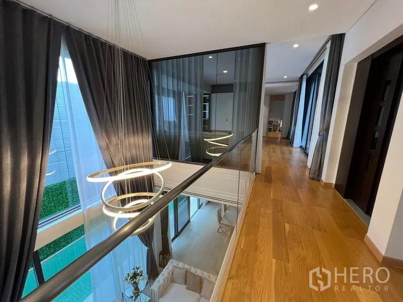 独立式住宅 出售在Suan Luang, Bangkok - 二层走廊玻璃栏杆与环形吊灯，可俯视客厅