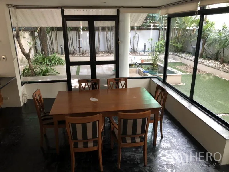 Detached House for rent in Bang Rak, Bangkok - Dining area with six chairs surrounded by picture windows overlooking the courtyard.